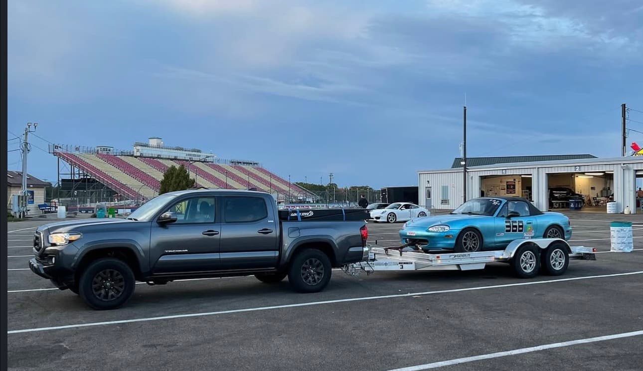 Race car loaded on a trailer behind a Tacoma truck